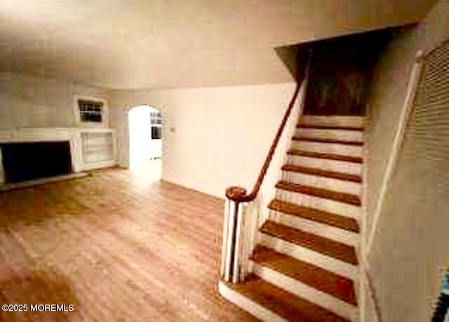 209 Broadway, Keyport, NJ 07735 - unfurnished living room with a fireplace, arched walkways, stairway, and wood finished floors