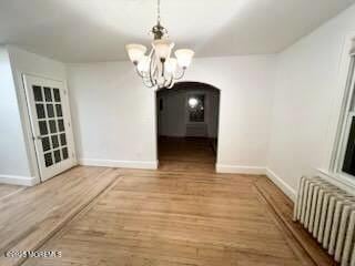 209 Broadway, Keyport, NJ 07735 - unfurnished dining area with radiator heating unit, arched walkways, a chandelier, and baseboards