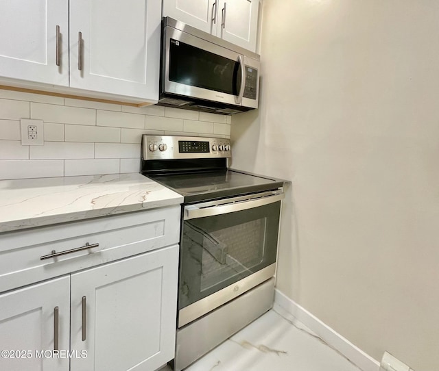 249 Center St, Little Egg Harbor, NJ 08087 - kitchen featuring backsplash, light stone countertops, baseboards, appliances with stainless steel finishes, and white cabinetry