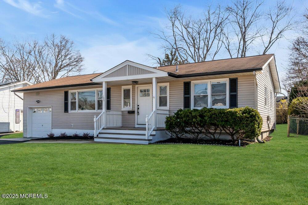 view of front facade featuring a front yard, a garage, and central AC