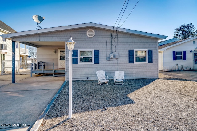 back of property featuring driveway, a carport, and fence
