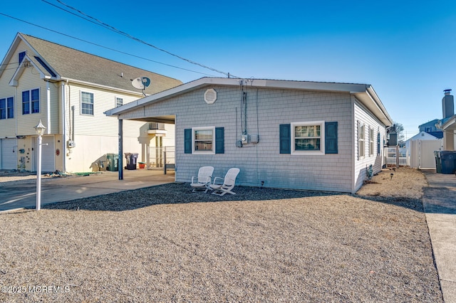 back of property with driveway, fence, a patio, and a carport