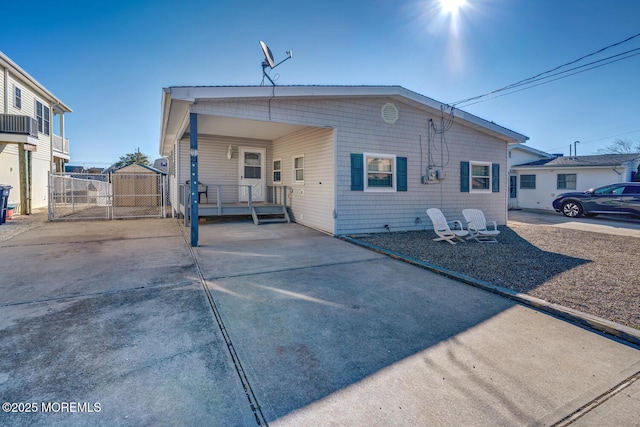 rear view of property featuring driveway, an attached carport, and fence