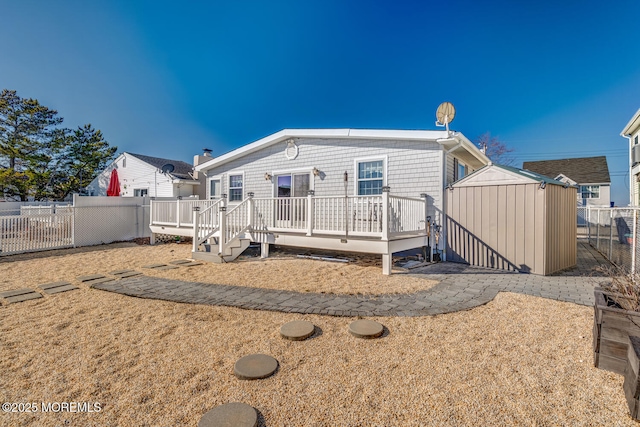 back of house with a fenced backyard, a shed, a wooden deck, and an outbuilding