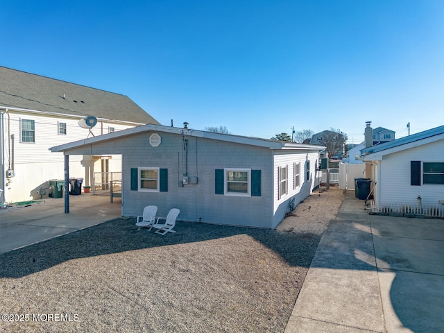 rear view of property with a patio, driveway, fence, and a carport
