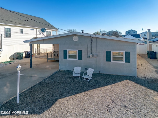 rear view of property featuring an attached carport, concrete driveway, and a patio area