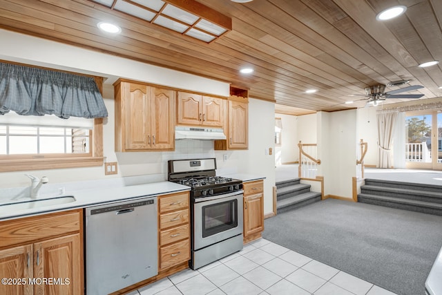 kitchen featuring stainless steel appliances, under cabinet range hood, a sink, wooden ceiling, and light colored carpet
