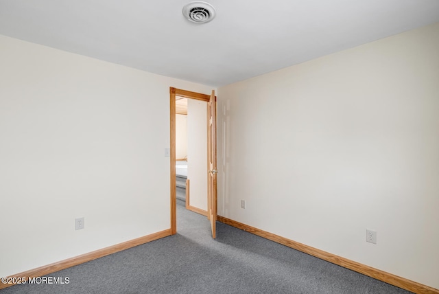 carpeted spare room featuring baseboards and visible vents