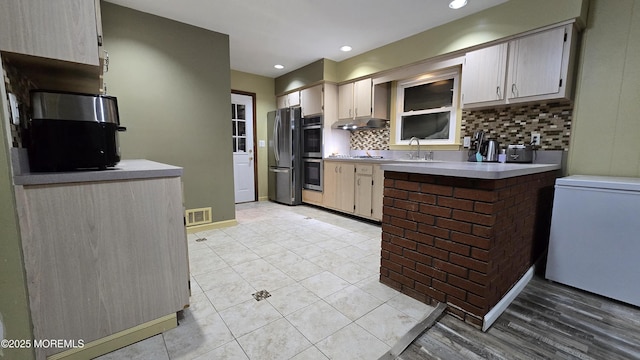 kitchen featuring visible vents, appliances with stainless steel finishes, light countertops, a sink, and decorative backsplash