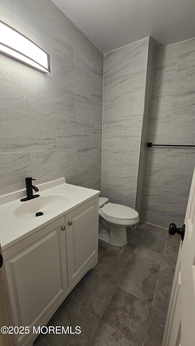 bathroom with toilet, tile walls, and vanity