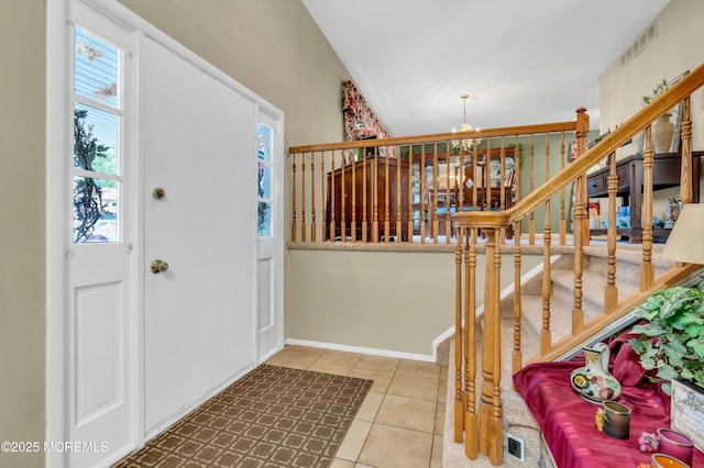 tiled foyer entrance with a chandelier and stairway