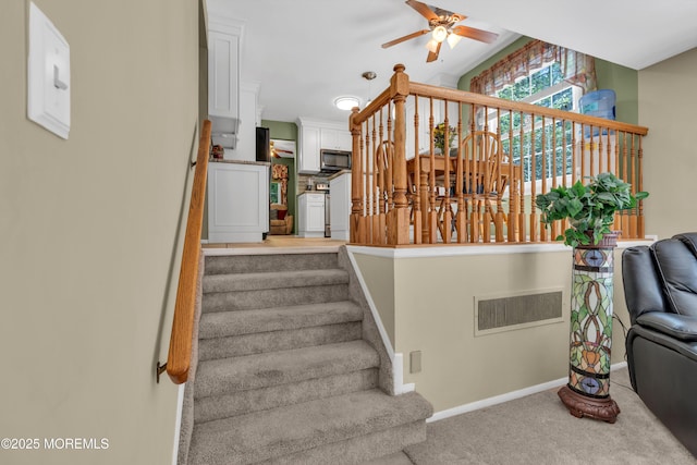 staircase featuring ceiling fan, carpet, and baseboards