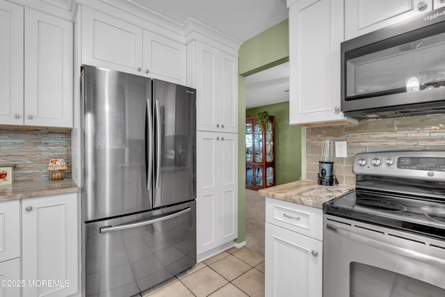 kitchen featuring stainless steel appliances, light tile patterned flooring, white cabinets, and backsplash