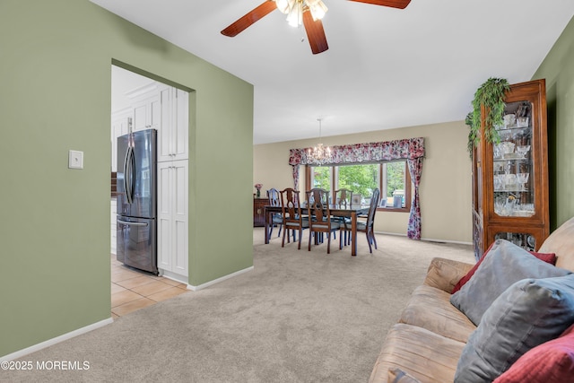 living room featuring light colored carpet, a ceiling fan, baseboards, and a chandelier