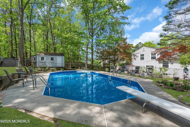 view of pool featuring a fenced backyard, a patio area, a diving board, an outbuilding, and a storage unit