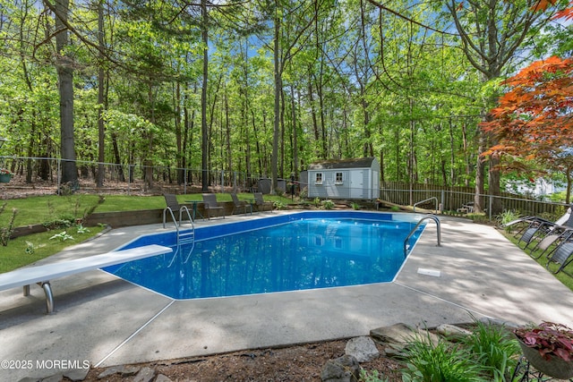 view of pool featuring a fenced backyard, a patio, an outdoor structure, a diving board, and a storage unit