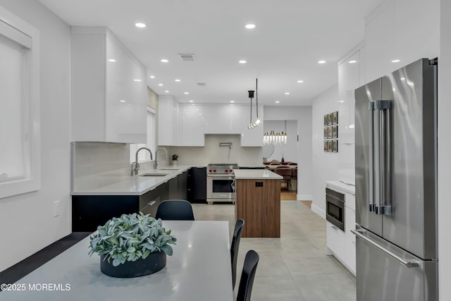 kitchen featuring high quality appliances, modern cabinets, a sink, white cabinetry, and a center island