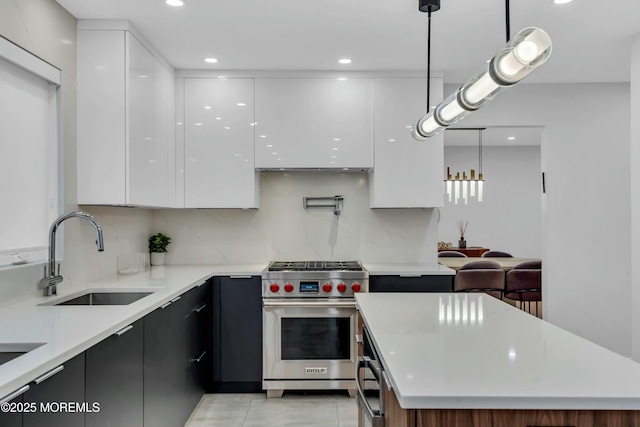 kitchen with modern cabinets, luxury range, a sink, white cabinets, and pendant lighting