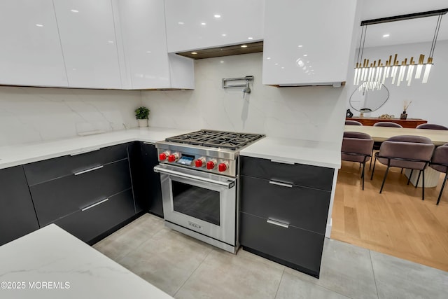 kitchen featuring modern cabinets, designer range, white cabinets, and backsplash