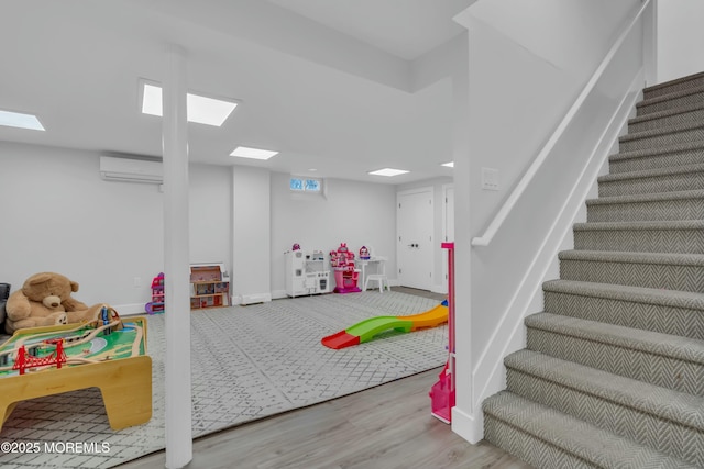playroom featuring a wall mounted AC, wood finished floors, and baseboards