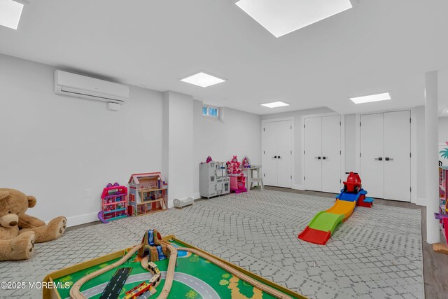 game room with a wall mounted AC and baseboards