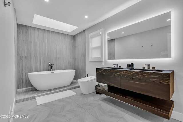 full bath with a skylight, a soaking tub, vanity, toilet, and recessed lighting
