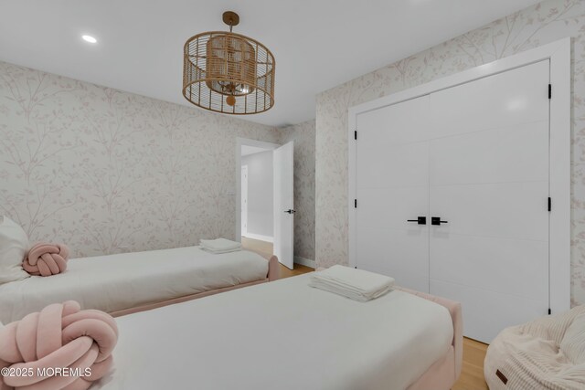 bedroom featuring wallpapered walls, wood finished floors, recessed lighting, a chandelier, and a closet