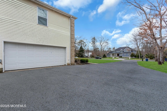 view of property exterior with driveway, a residential view, and a garage