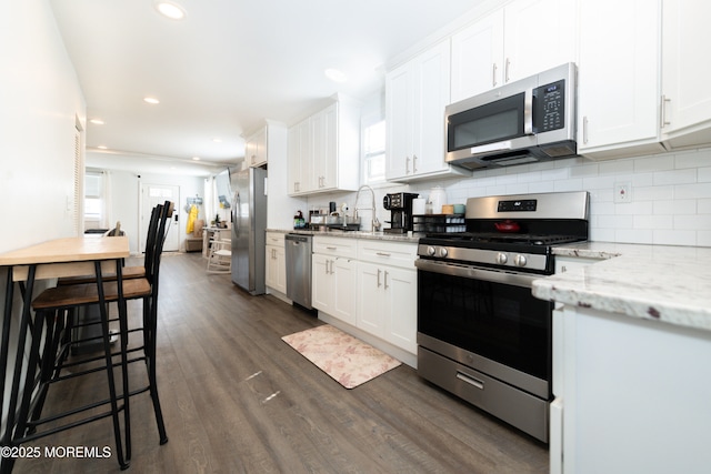 kitchen with white cabinets, dark wood-style flooring, tasteful backsplash, and appliances with stainless steel finishes