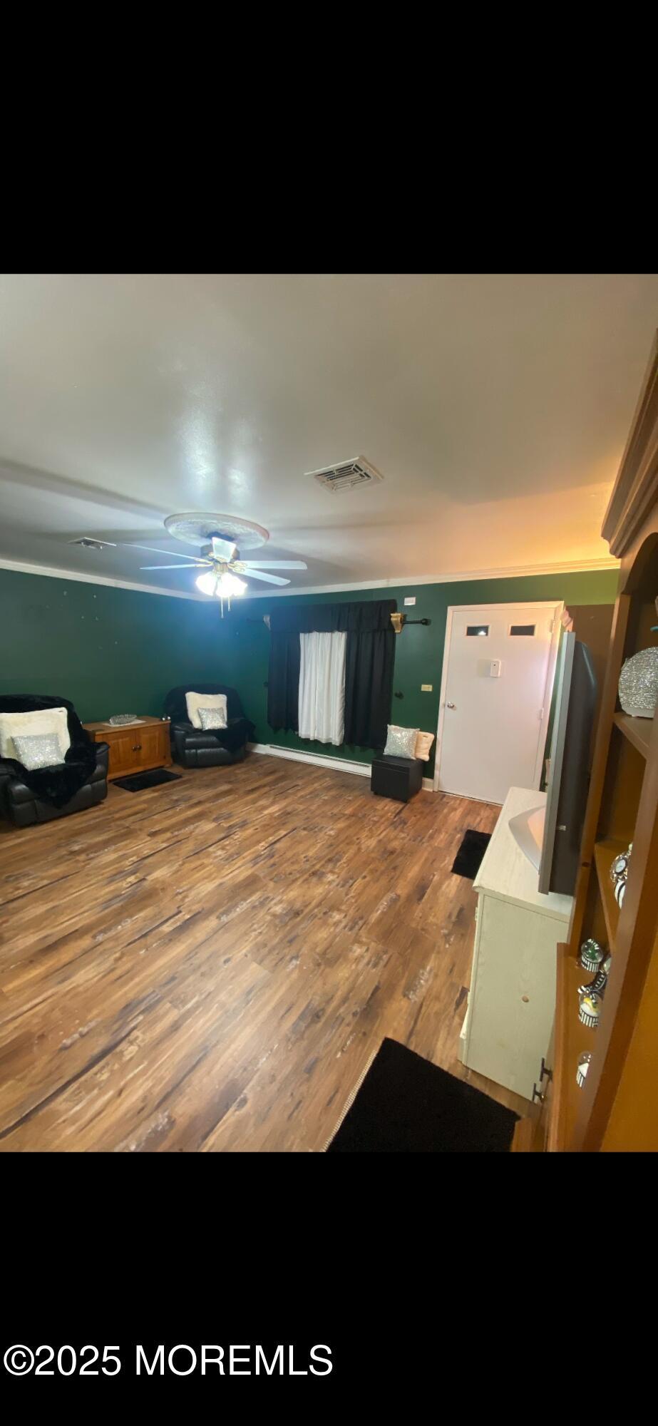 interior space with visible vents, ceiling fan, and wood finished floors