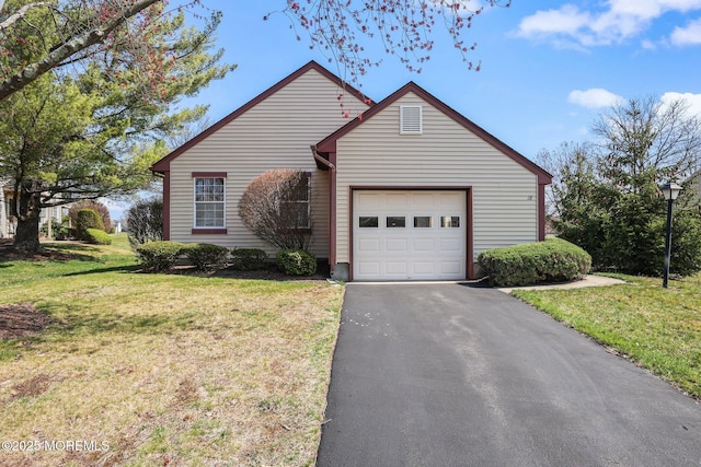 ranch-style home featuring an attached garage, a front lawn, and aphalt driveway