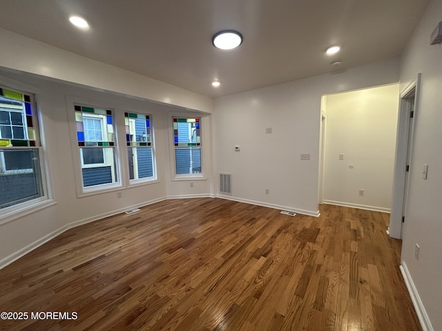 empty room featuring wood finished floors, baseboards, visible vents, and recessed lighting