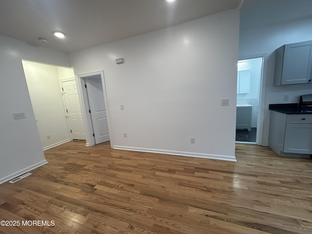 spare room featuring visible vents, baseboards, and wood finished floors