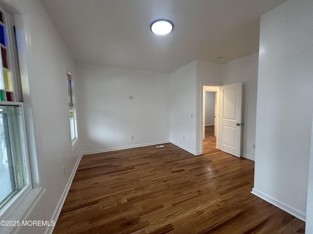 empty room with dark wood-style flooring and baseboards