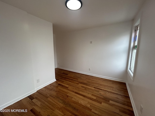 spare room featuring dark wood-style flooring and baseboards