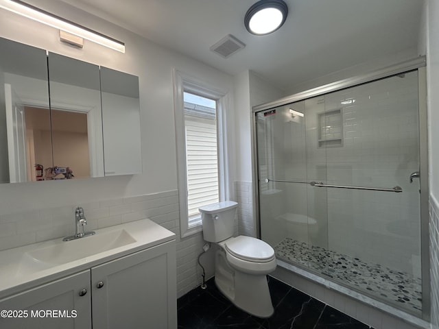 full bath featuring vanity, visible vents, toilet, tile walls, and a stall shower