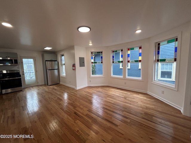 unfurnished living room featuring baseboards, electric panel, and dark wood finished floors