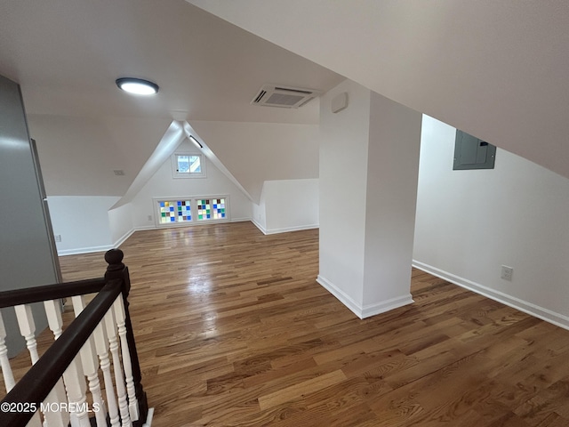 additional living space featuring electric panel, vaulted ceiling, visible vents, wood finished floors, and baseboards