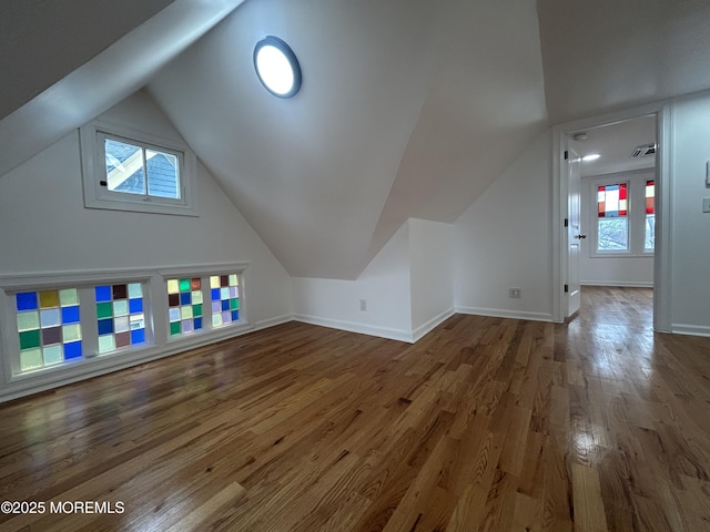 additional living space featuring a wealth of natural light, lofted ceiling, baseboards, and wood finished floors