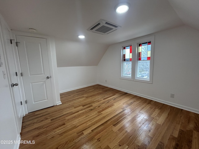 additional living space with wood finished floors, baseboards, and vaulted ceiling