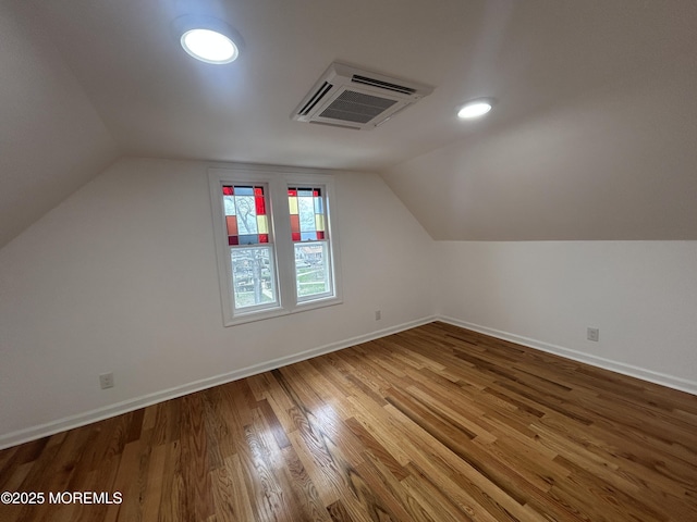 additional living space featuring wood finished floors, baseboards, and vaulted ceiling