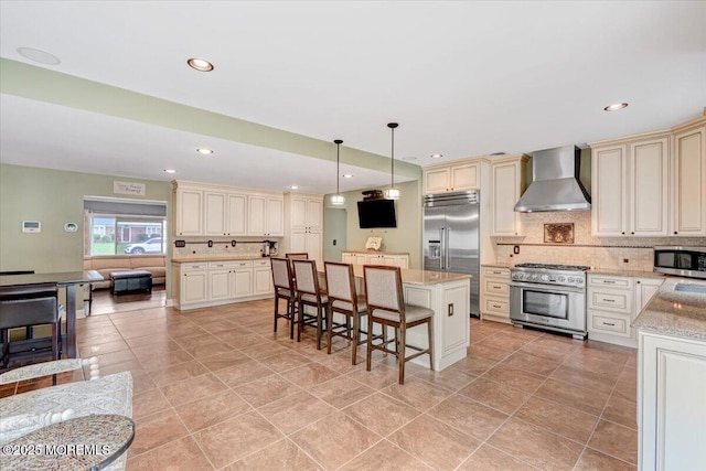 77 Warren Dr, Aberdeen, NJ 07747 - kitchen with wall chimney exhaust hood, cream cabinetry, high end appliances, decorative backsplash, and recessed lighting