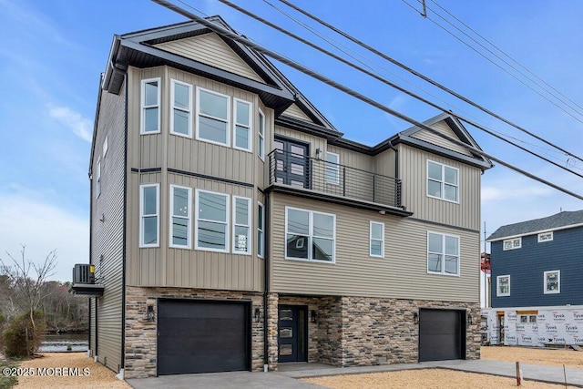 multi unit property with board and batten siding, an attached garage, stone siding, and a balcony