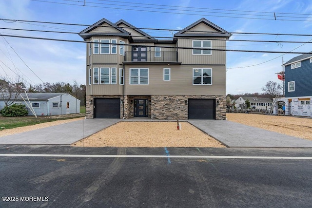 view of front of home with concrete driveway, stone siding, and a balcony