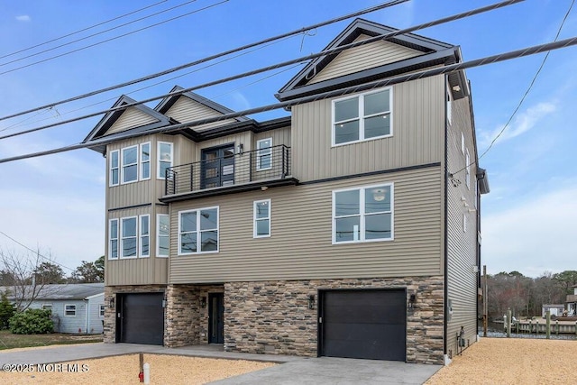 view of front of property with driveway, a balcony, stone siding, and an attached garage