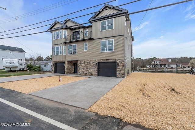 view of front facade featuring board and batten siding, a garage, stone siding, a balcony, and concrete driveway