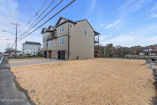 view of home's exterior featuring driveway, stone siding, and a garage