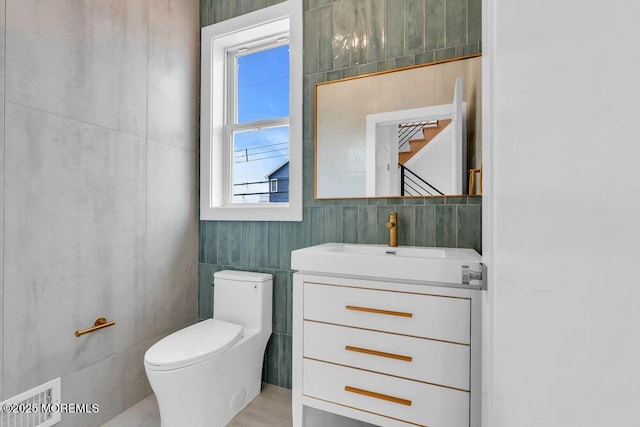 bathroom featuring vanity, visible vents, tile walls, and toilet