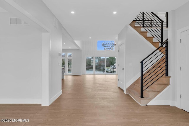 interior space featuring an inviting chandelier, visible vents, wood finished floors, stairs, and baseboards