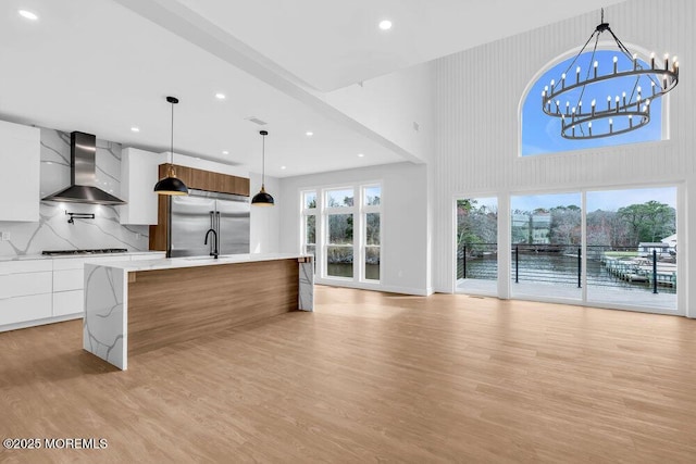 kitchen with wall chimney exhaust hood, modern cabinets, cooktop, light wood-type flooring, and white cabinetry